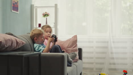 un bebé lindo aprende a usar una consola de juegos con su hermana mayor