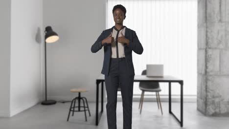 portrait of smiling businesswoman wearing suit giving thumbs up gesture standing in modern open plan office