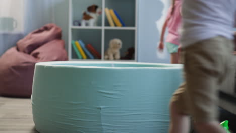 little kids run and gather balls for dry pool in living room