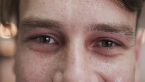 portrait close up of eyes of happy caucasian male chef smiling in kitchen, slow motion