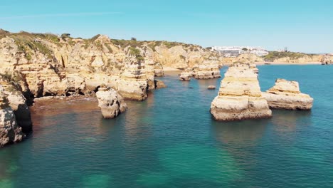 volar a través de la idílica costa rocosa del océano lagos en algarve, portugal - toma aérea