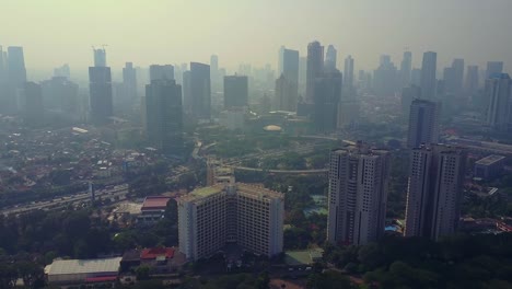 aerial view of jakarta city with a circle intersection of highway and skyscrapers in the misty morning, shot in 4k resolution