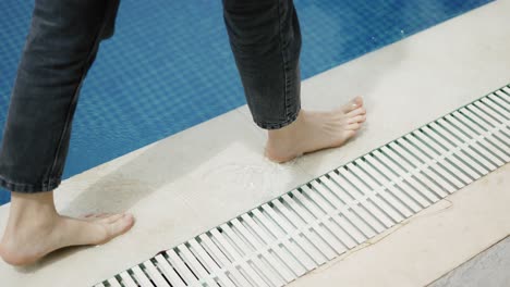 A-girl-with-bare-feet-is-walking-along-the-edge-of-a-pool