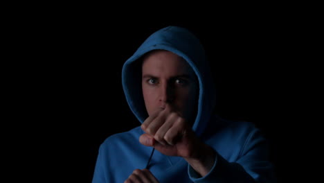 sporty young man boxing on black background