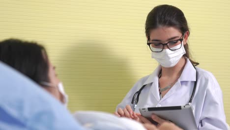 un médico con una máscara facial habla con competencia con el paciente en la sala del hospital