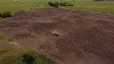 toma de órbita aérea de conducir tractor arando tierras de cultivo durante el día soleado - levantamiento de polvo - provincia rural de buenos aires, argentina - imágenes de drones de 4k