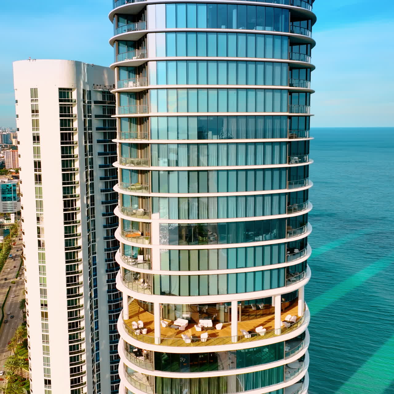 Drone approaching the beautiful high-rise apartment block on the coast of the Atlantic Ocean. Miami Beach architecture on sunny day.