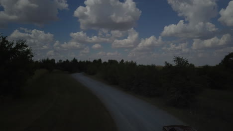 Aerial-shot-of-a-car-driving-along-a-countryside-road-and-then-continuing-to-driving