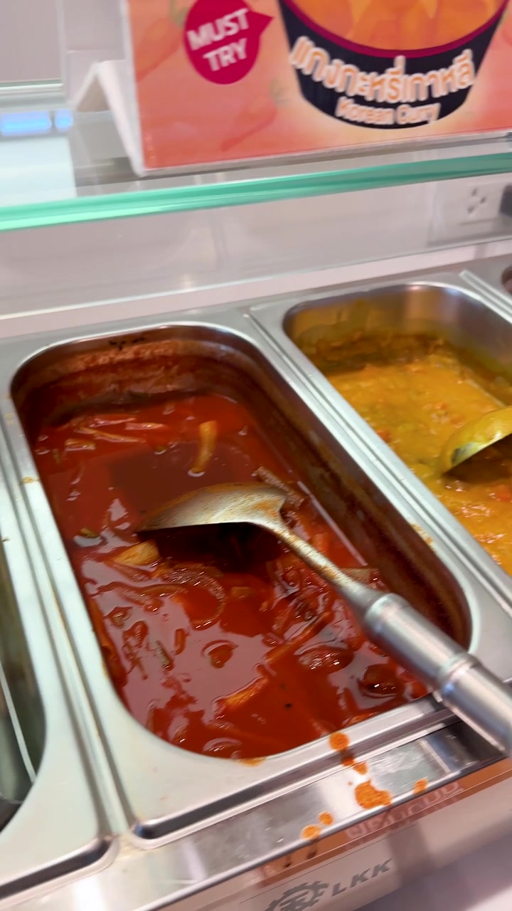La telecamera panoramica su vari piatti coreani in vassoi di metallo in una mensa a Bangkok, Thailandia