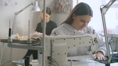 dressmaker sewing clothes. fashion designer sewing new model of clothes. seamstress woman works on sewing machine in tailoring workshop business. she stitches details for future clothing.