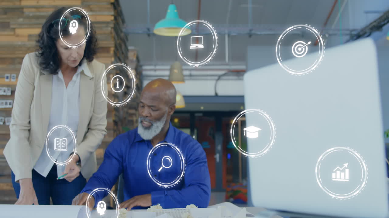 Animation of business icons over diverse business people discussing work