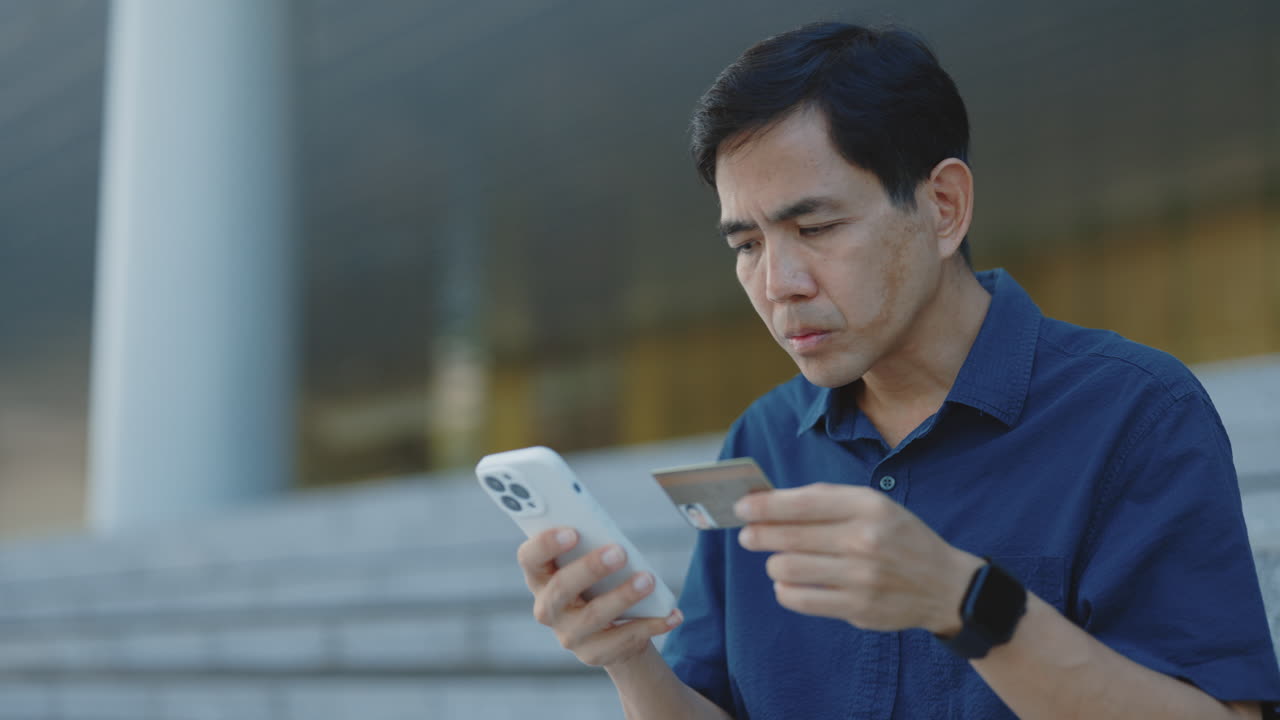 Man Checking Credit Card Details on Mobile Phone