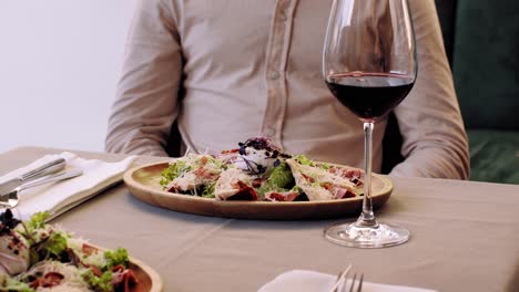 camarero sirviendo ensalada césar y vino