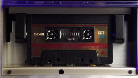 close up of audio cassette tape playing or recording in vintage deck player from 1980's