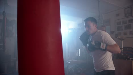 un boxeador se entrena en una sala de entrenamiento con un saco de boxeo