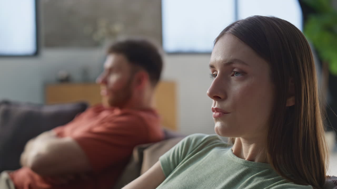 Couple experiencing relationship problem sitting separately on couch closeup