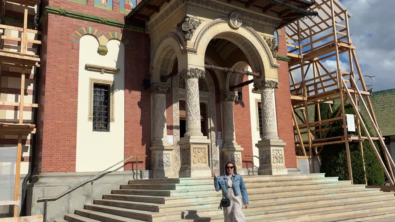 Tourist woman walking by Sinaia monastery in Romania. Dolly out