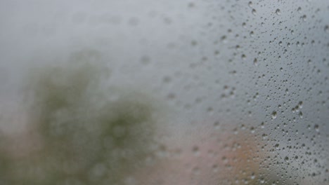 a close-up and narrow focus view of rainy glass as rain drops are seen on a window