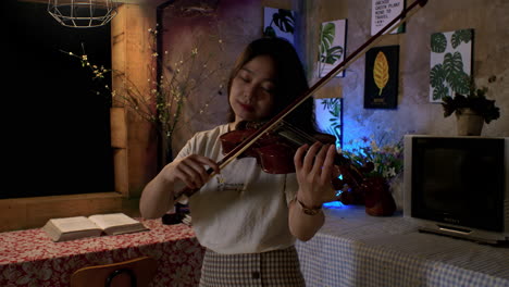 cute female musician enjoys playing melodic tunes on violin at home