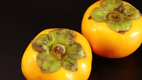 two persimmons rotating on a black background