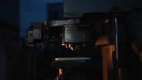 industrial machine pressing a component in a dimly lit factory