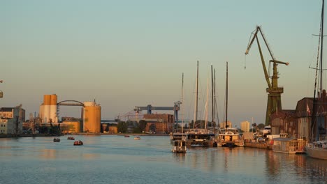 Gdańsk-shipyard-with-cranes-and-boats,-in-golden-sunset-light