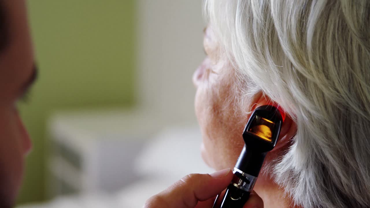 médico examinando el oído de los pacientes con otoscopio