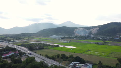 aerial drone forward moving shot of mountain being destroyed to get minerals next to ah 1 highway and railway tracks on a cloudy day in phan rang, vietnam