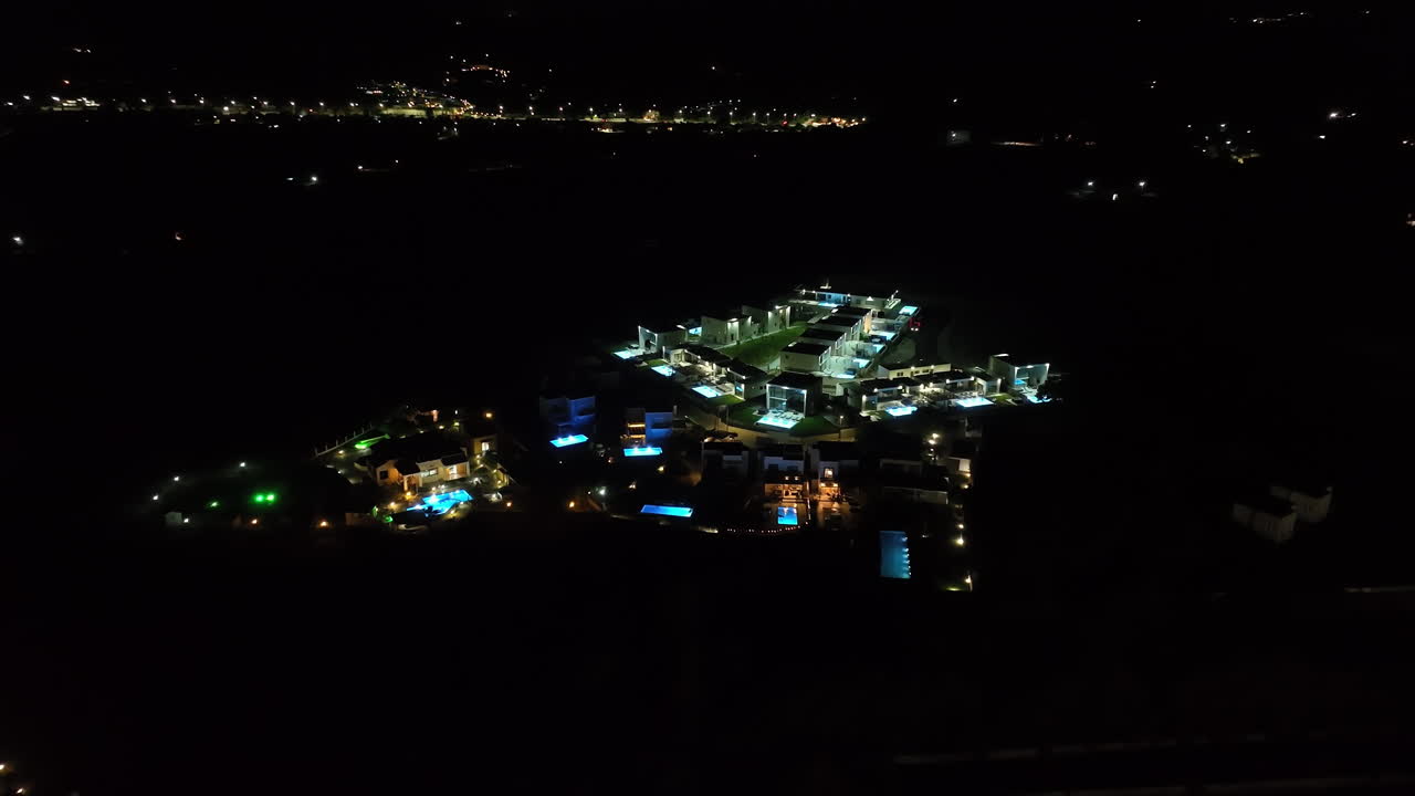 Panoramic drone shot circling upscale hilltop, holiday villas, night in Greece
