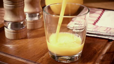 Orangensaft-In-Ein-Glas-Gießen,-Das-Morgendliche-Frühstück.-Zeitlupe-Mit-Rotierender-Kamerafahrt.