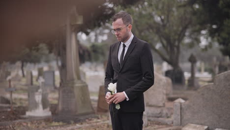 Funeral,-cemetery-and-man-with-flower-by-tombstone