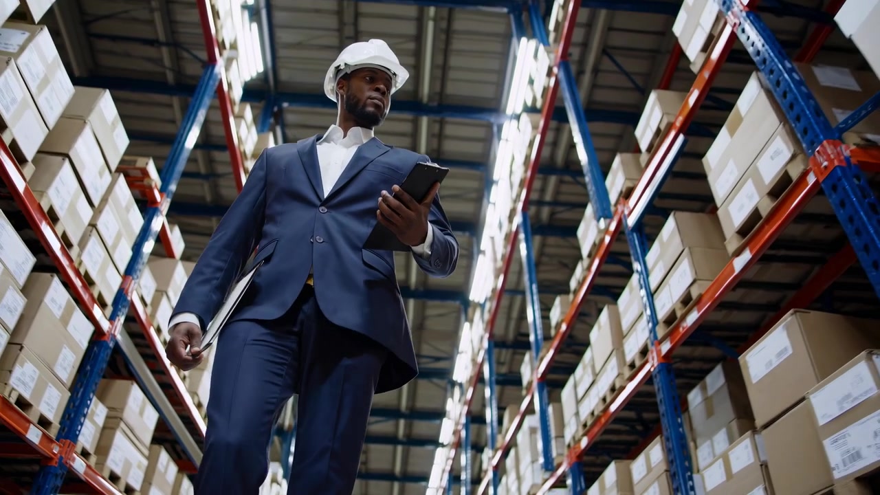 Professional Black Man in Hard Hat Inspecting Warehouse Inventory