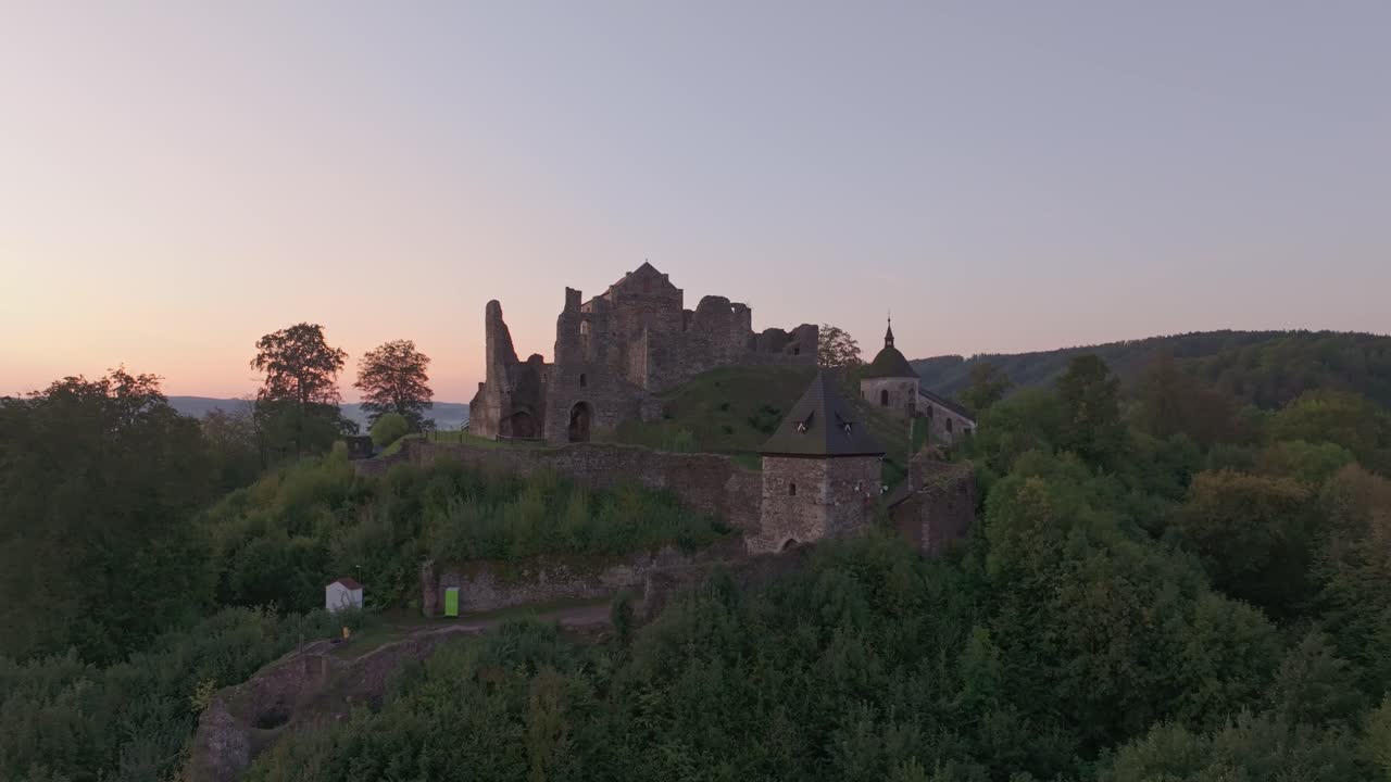 Ripresa drone del Castello di Potstejn immerso in una lussureggiante foresta all'alba.