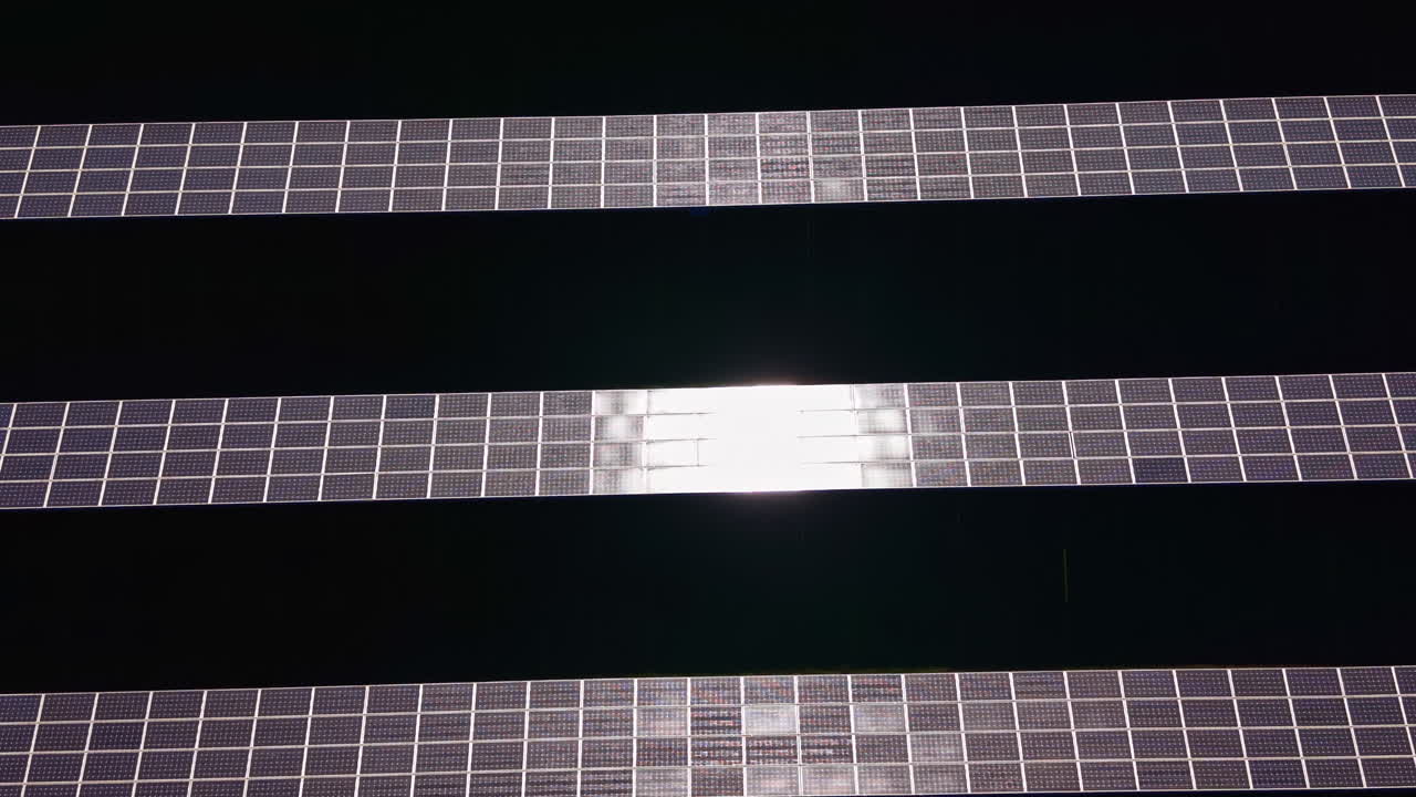 Solar panels arranged in rows capture sunlight in an energy production site during a sunny afternoon