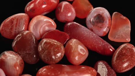 red jasper stones rotate smoothly against a black backdrop, highlighting their rich colors and polished surfaces under soft lighting