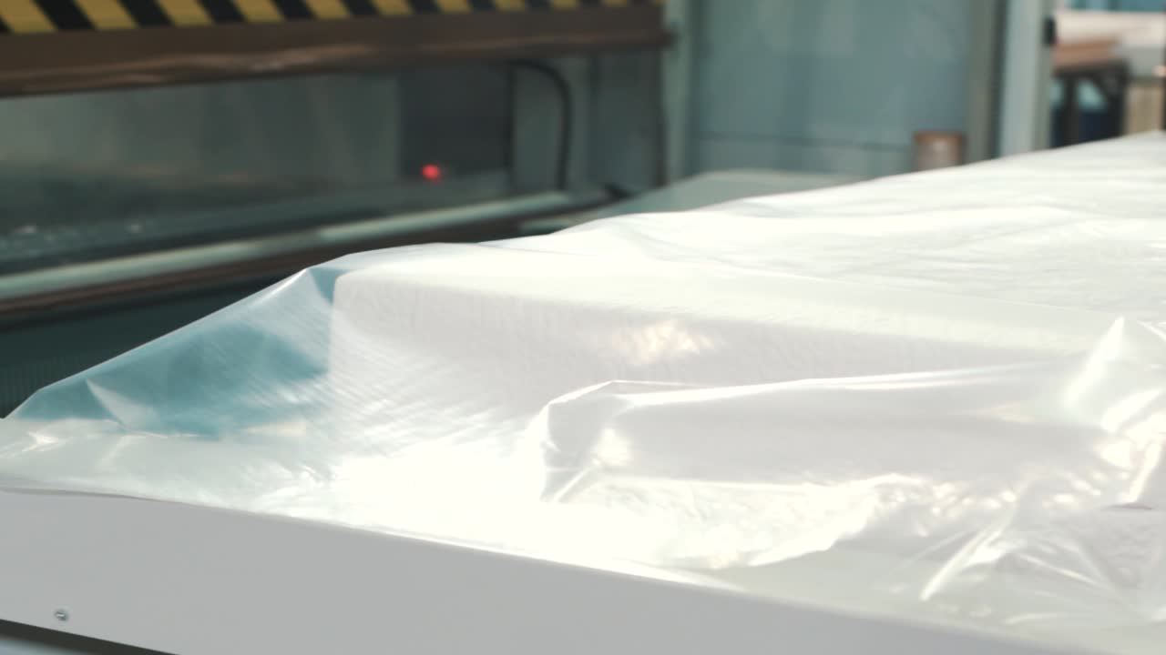 진공 포장 전에 스트레치 필름으로 매트리스를 포장하는 선형 공장 생산 클로즈업