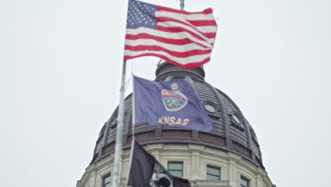 .Flaggen-Wehen-In-Zeitlupe-Vor-Dem-Kansas-State-Capitol-Building-In-Topeka,-Kansas,-Mit-Nahaufnahmevideo