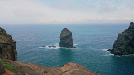 Drone rock formation ocean in summer. Tourists walk along rugged coastal cliffs