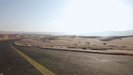 driving down an empty road into the beautiful abu dhabi sand desert on a hot day