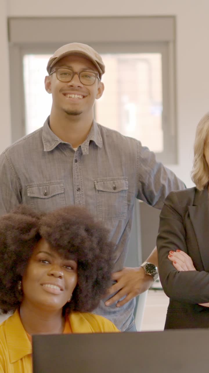 Coworking team smiling at camera standing and sitting together