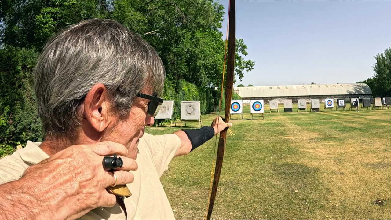 Arciere senior che mira con un arco ricurvo in un campo di tiro all'aperto