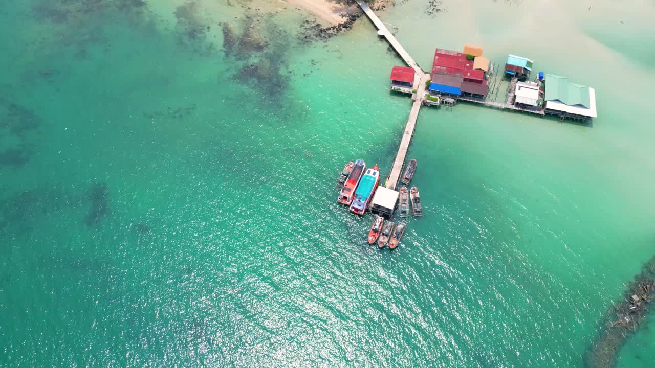 Aerial view of a tropical pier with boats and houses over turquoise water