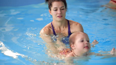 happy smiling toddler is jumping and diving under the water in the swimming pool. an underwater shot. slowmotion