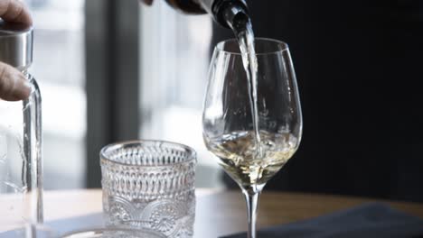 Slow-Motion-Close-Up-of-African-American-Hand-Pouring-White-Wine-Into-Wine-Glass