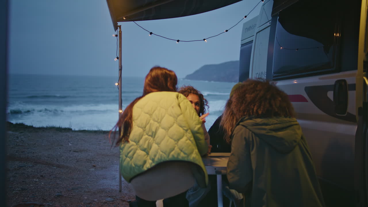 amigos felices reunidos en una furgoneta en la sombría noche de la costa del océano.
