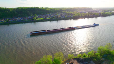 AERIAL---Pusher-boat-and-barge,-reflection-on-Ohio-River,-Ironton,-Ohio,-circling-shot