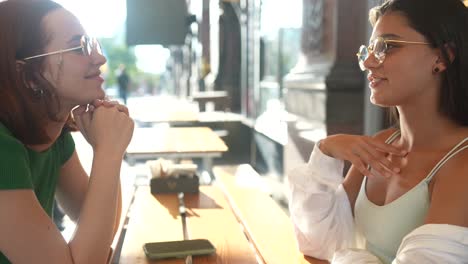 dos mujeres teniendo una conversación en un café al aire libre