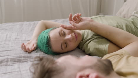 man touching his girlfriend's cheek while lying on the bed at home