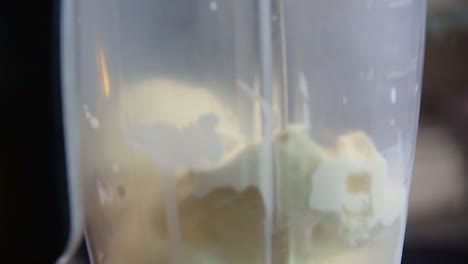 agregar leche a cámara lenta en una licuadora con bolas de helado de vainilla para preparar batido - movimiento de cámara