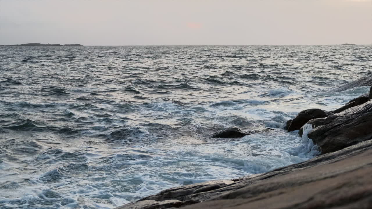 Waves hitting rocks. Evening shot. Dark ocean, white waves.